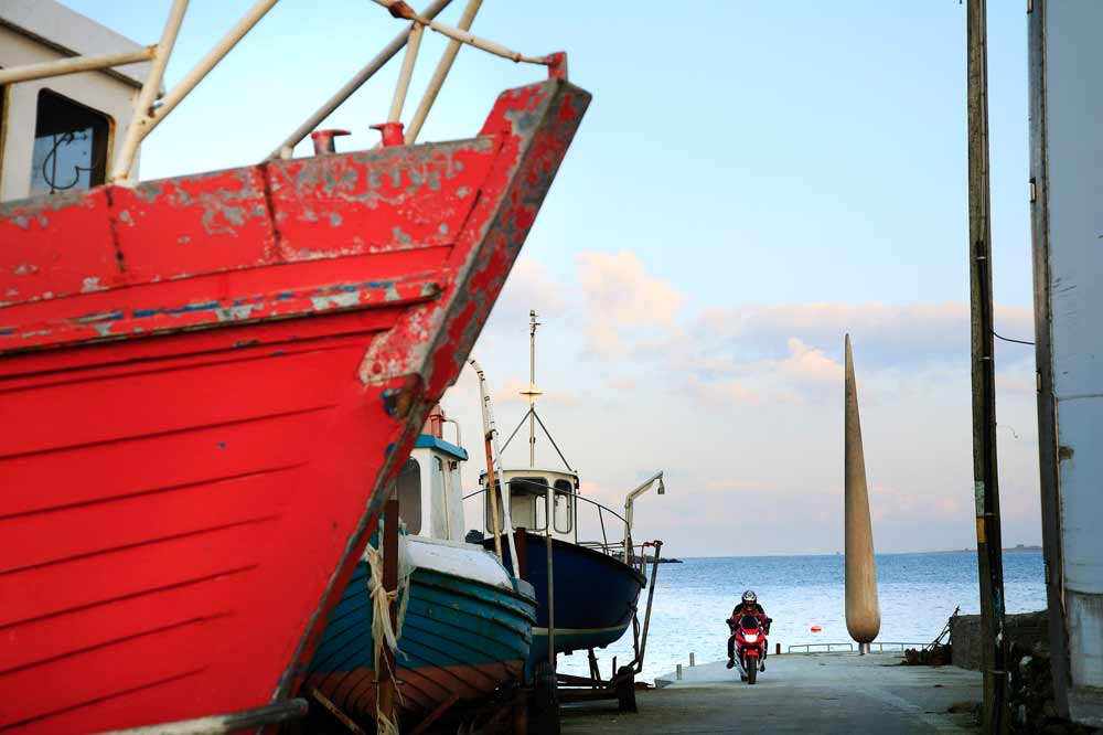 photo of the fid with a red boat in the four groung and a man on a motorbike