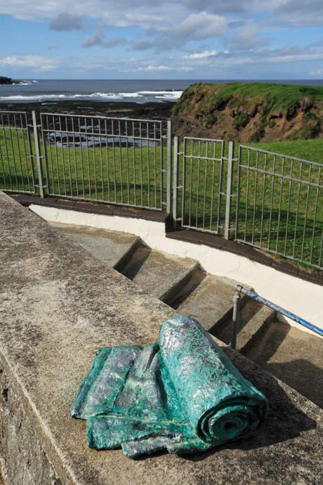 "photo of two Dry sculpures on a wall over looking the sea"