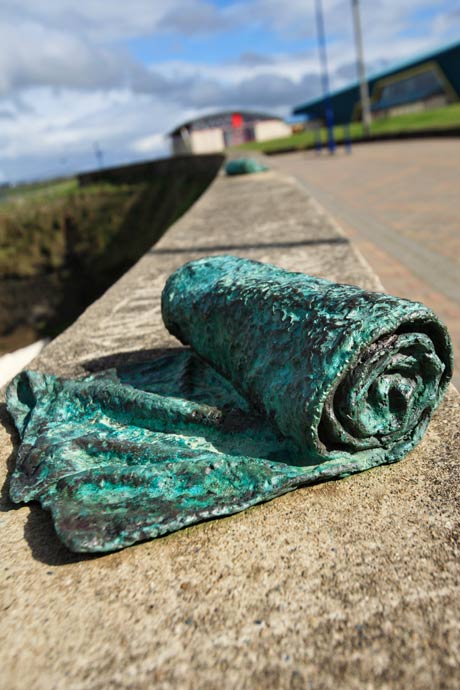 photo of two Dry sculpures on a wall over looking the sea