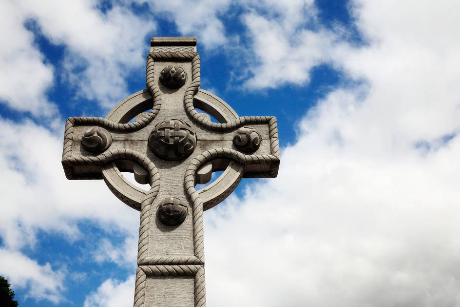 photo of stone cross, blue sky background